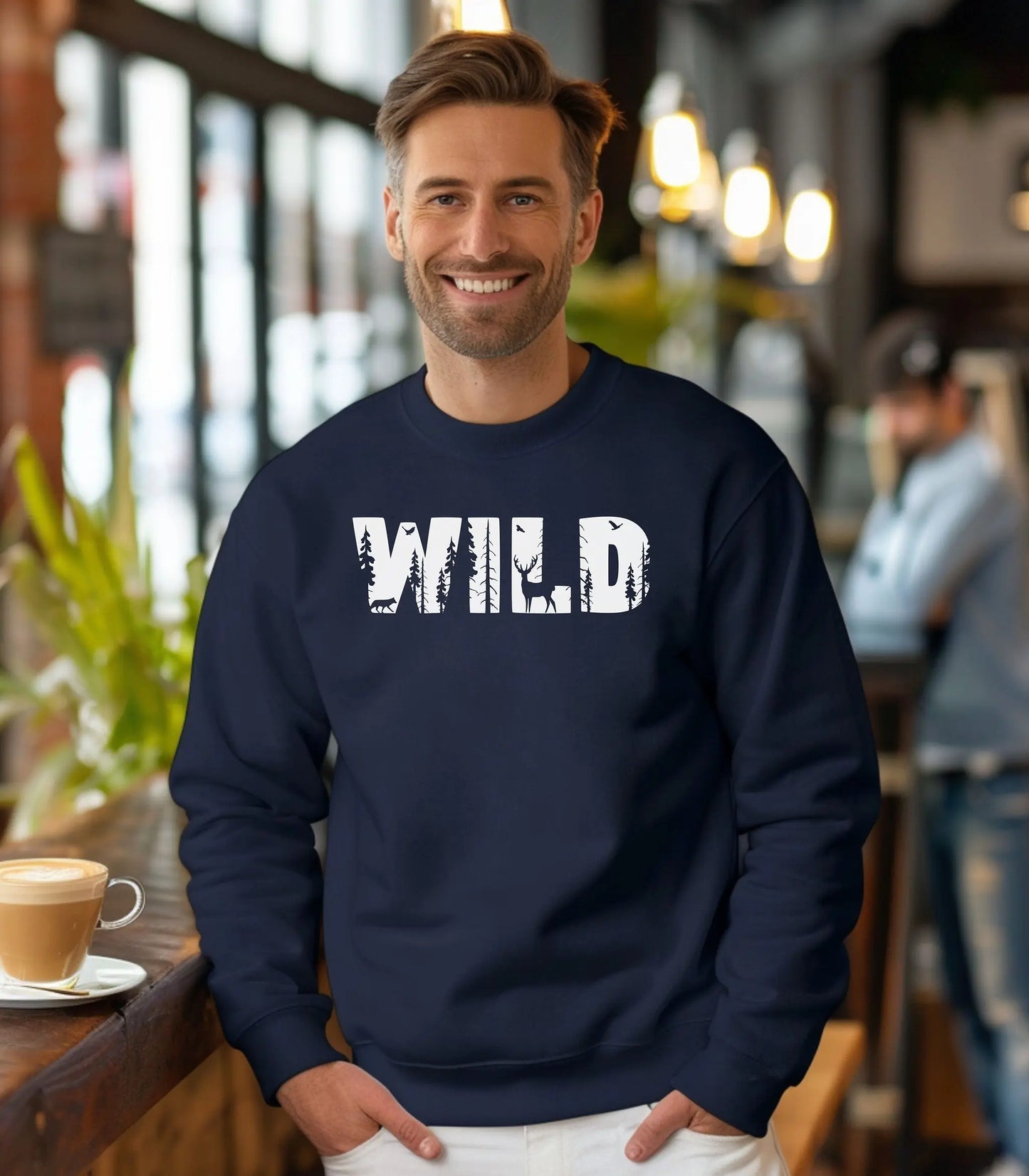 Man wearing a navy blue sweatshirt with 'WILD' printed on it, standing in a casual setting.