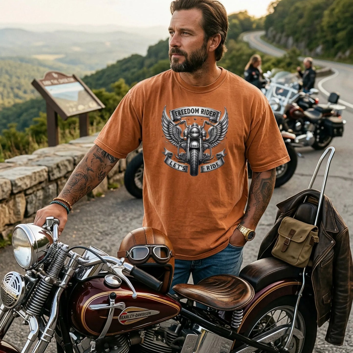 Man wearing a yam 'Freedom Rider' t-shirt standing next to a motorcycle with scenic background
