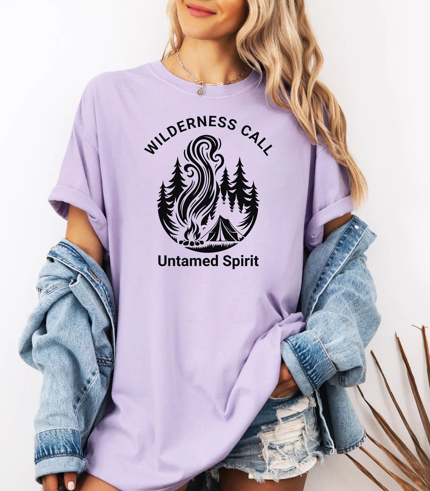 Person wearing a orchid t-shirt with wilderness call untamed spirit graphic and text.