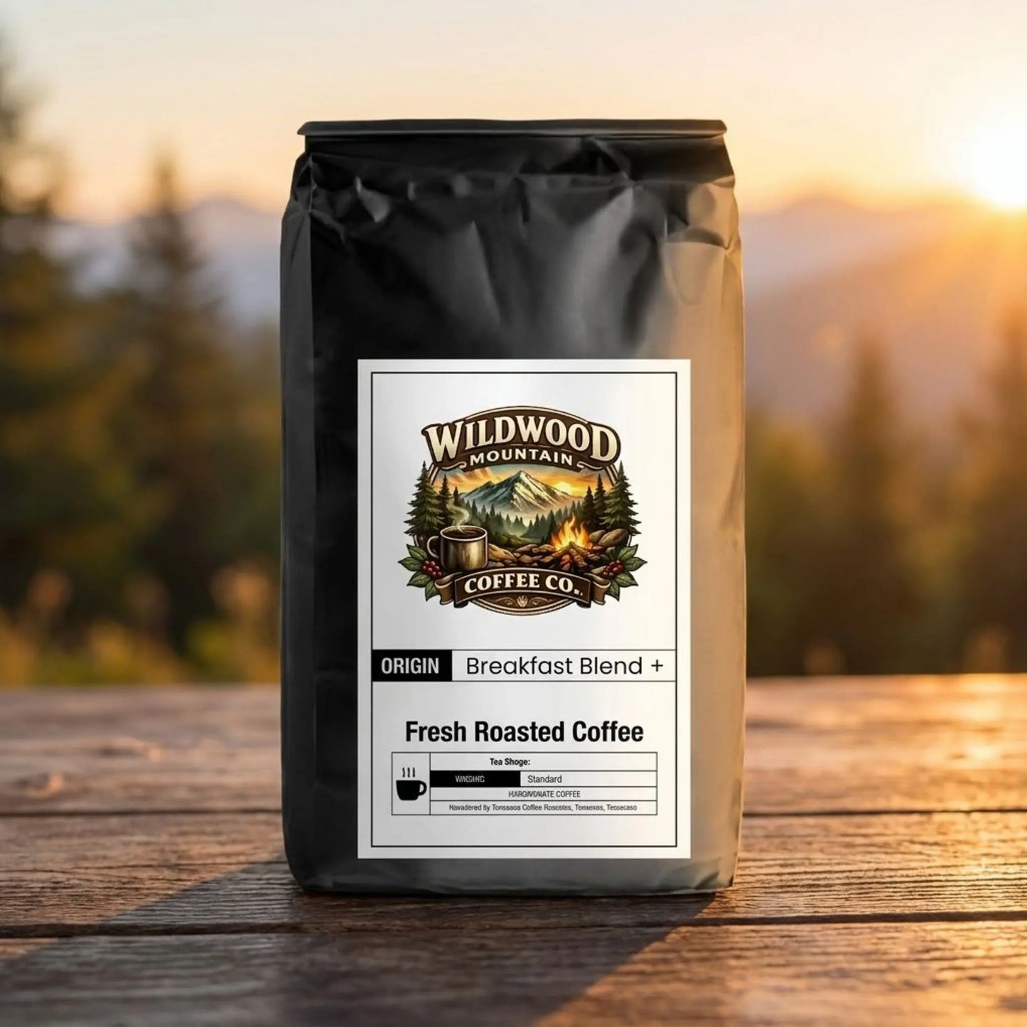 Wildwood Mountain Coffee Co - Breakfast Blend Plus Robusto - Outdoors sitting on a wood outdoor table with scenic mountains and trees in the background.